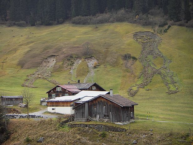 An mehreren Stellen ist ein Hang vor einem Bauernhaus ins Rutschen gekommen. 
