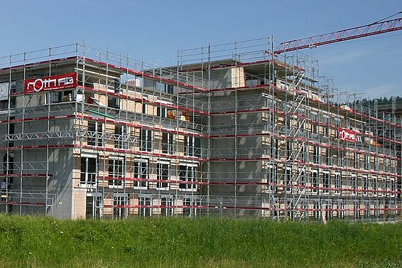 Mehrere mehrstöckige Wohngebäude in Uznach im Rohbau mit Gerüsten und Baukran, umgeben von grünem Gras
