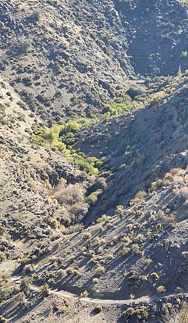Berglandschaft mit steilen, felsigen Hängen und vereinzeltem niedrigem Bewuchs unter klarem Himmel